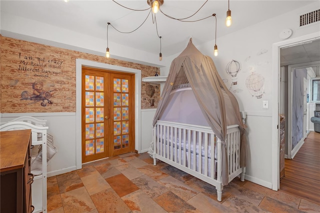 2014 E Broad St, Tampa, FL 33610 - bedroom with visible vents, stone tile floors, wainscoting, and french doors