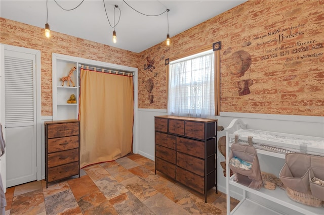 2014 E Broad St, Tampa, FL 33610 - bedroom featuring a wainscoted wall, wallpapered walls, and stone finish flooring