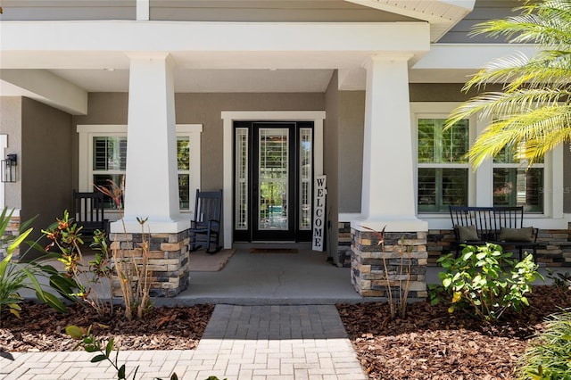 entrance to property featuring a porch and stucco siding