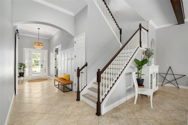 foyer entrance with stairway, arched walkways, and a high ceiling