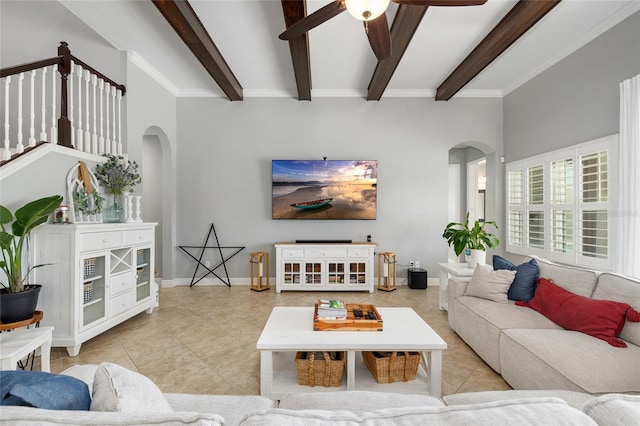 tiled living area featuring baseboards, arched walkways, ceiling fan, and beam ceiling