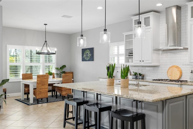 kitchen with wall chimney range hood, tasteful backsplash, open shelves, stainless steel gas stovetop, and white cabinetry