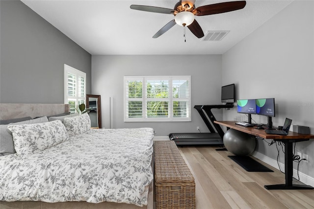 bedroom featuring visible vents, a ceiling fan, baseboards, and wood finished floors