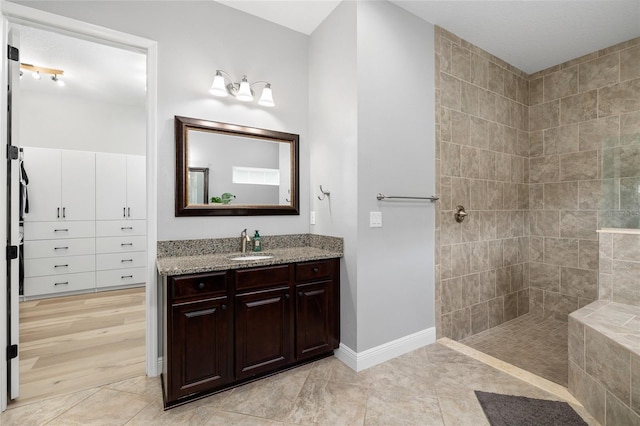 bathroom featuring vanity, baseboards, walk in shower, and tile patterned floors