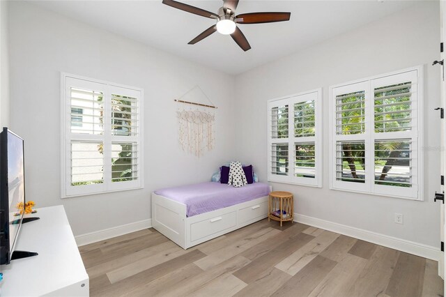 bedroom with light wood-style floors, baseboards, and ceiling fan