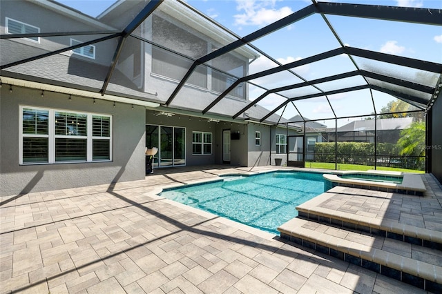 view of swimming pool with glass enclosure, a patio area, and a pool with connected hot tub