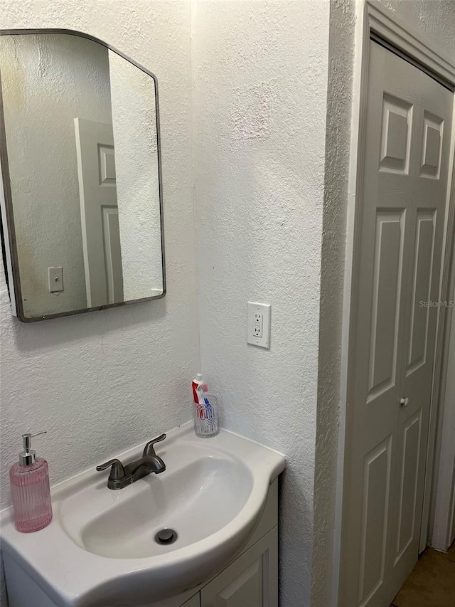 bathroom featuring a textured wall and vanity