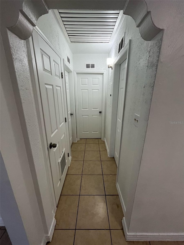 corridor with light tile patterned floors, baseboards, and visible vents