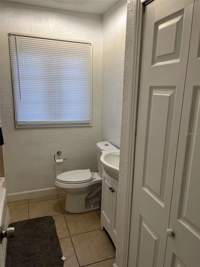 bathroom featuring vanity, baseboards, tile patterned flooring, and toilet