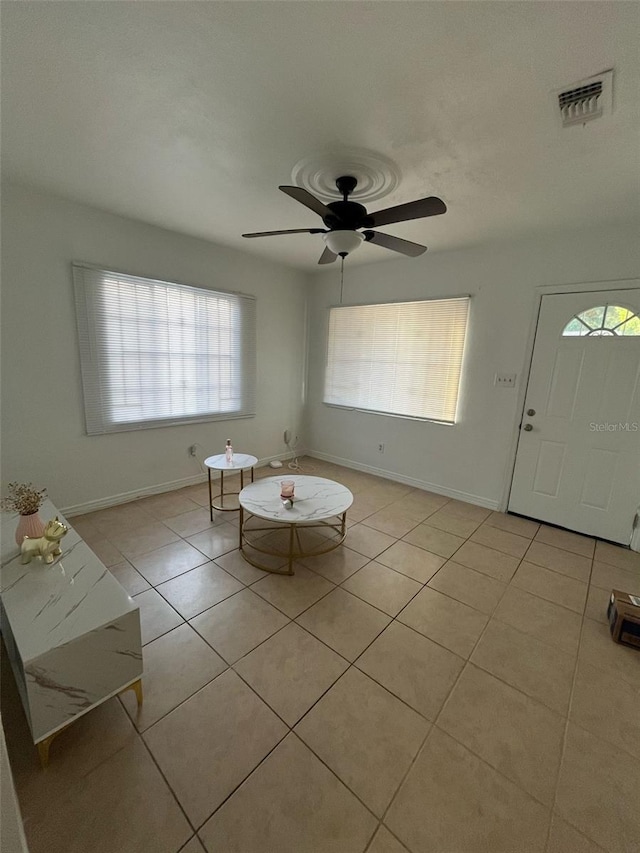 interior space with baseboards, a ceiling fan, light tile patterned flooring, and visible vents