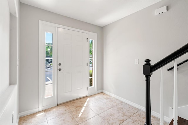 entryway with light tile patterned flooring, stairway, and baseboards