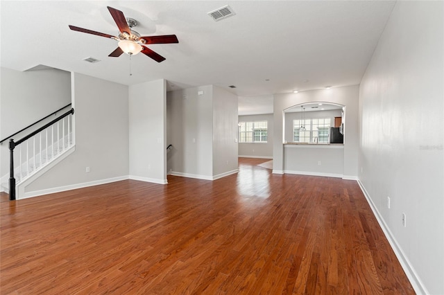 unfurnished living room with stairway, ceiling fan, wood finished floors, and visible vents