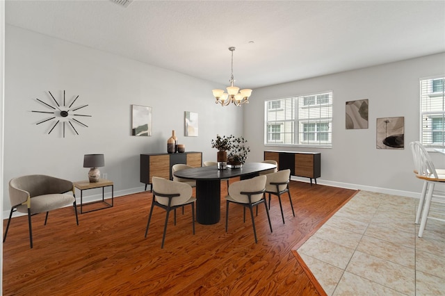 dining space featuring an inviting chandelier, wood finished floors, and baseboards