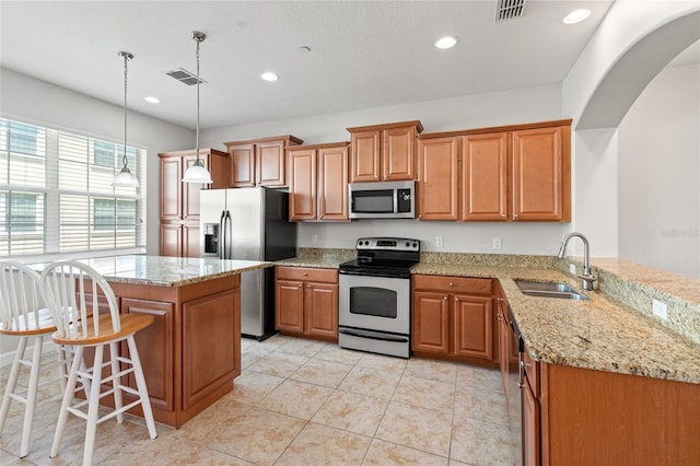 kitchen featuring light stone countertops, stainless steel appliances, visible vents, and a sink