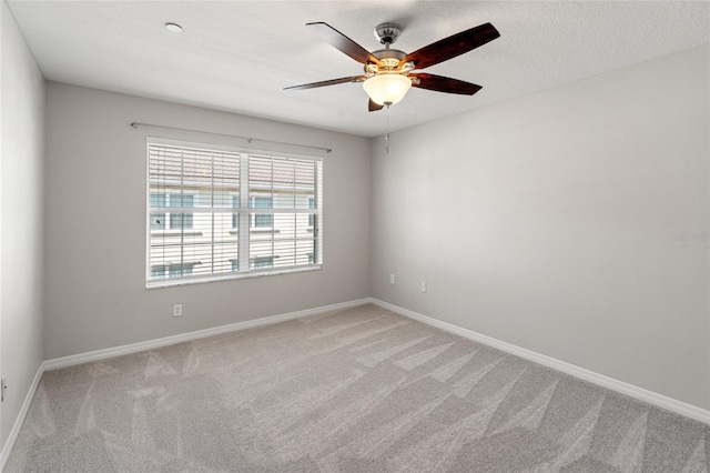 spare room with ceiling fan, baseboards, and light carpet