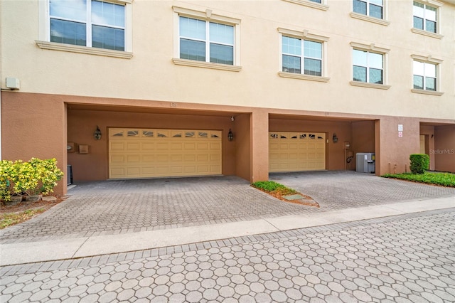 multi unit property with a garage, driveway, and stucco siding