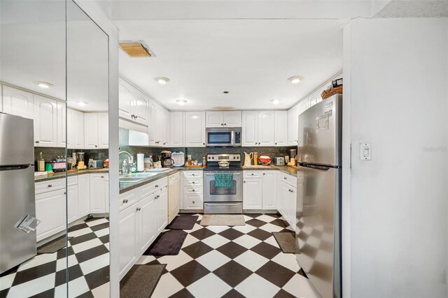 1 Key Capri Unit 608E, Treasure Island, FL 33706 - kitchen with stainless steel appliances, dark floors, a sink, backsplash, and white cabinetry