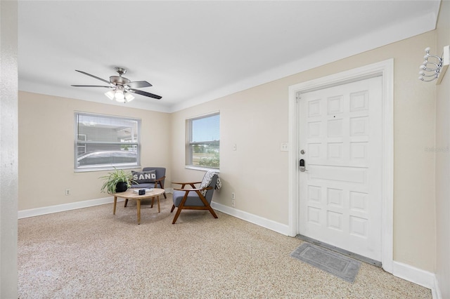 living area featuring baseboards and ceiling fan