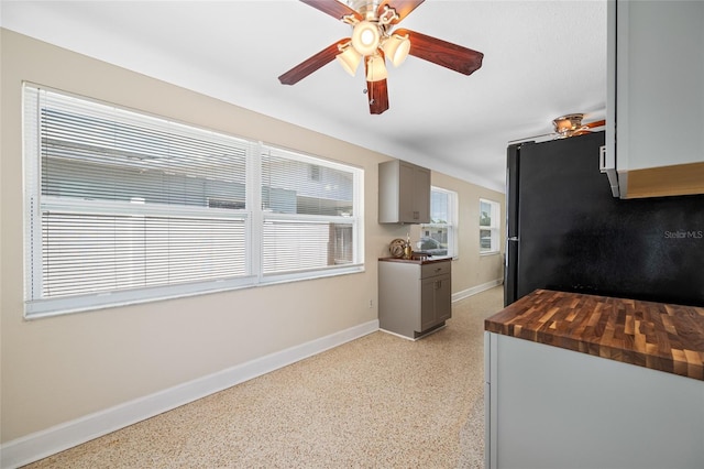 kitchen with a ceiling fan, light speckled floor, butcher block counters, baseboards, and freestanding refrigerator