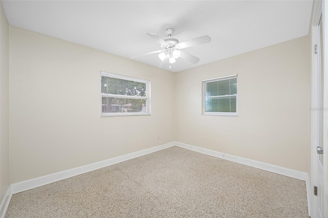 empty room featuring a ceiling fan, baseboards, and speckled floor