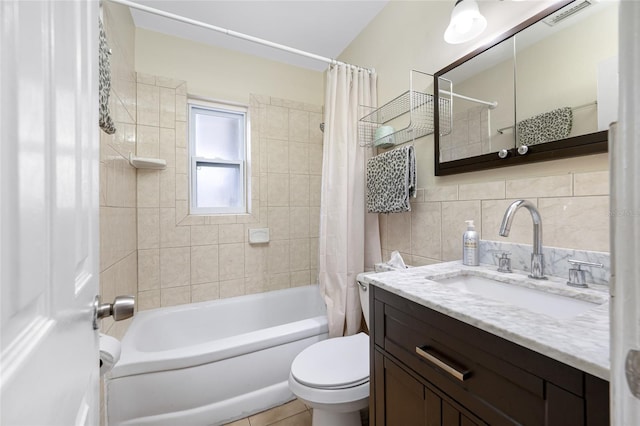 bathroom with shower / bath combo, vanity, tile walls, toilet, and visible vents