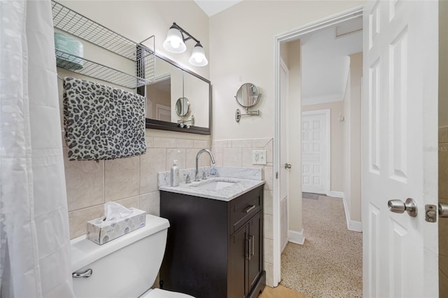 bathroom featuring toilet, vanity, and tile walls