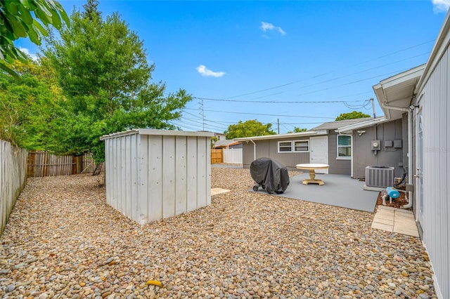 exterior space with a patio area, a fenced backyard, an outdoor structure, cooling unit, and a storage unit