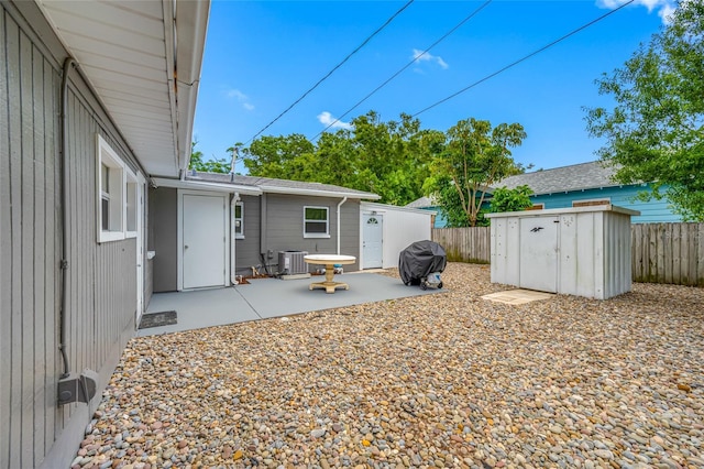 view of yard with a fenced backyard, a storage shed, cooling unit, and a patio