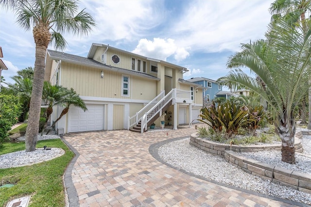 raised beach house featuring stairway, decorative driveway, and a garage