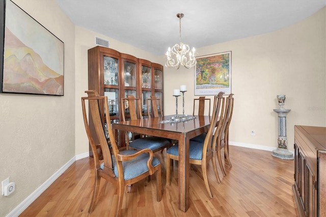 dining space featuring light wood-style floors, a chandelier, and baseboards