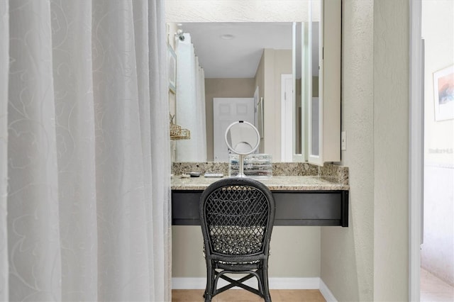 bathroom featuring a textured wall and baseboards