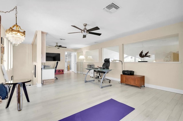 workout room featuring wood finished floors, ceiling fan, baseboards, and a chandelier