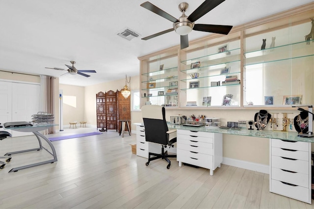 home office featuring a ceiling fan, built in desk, light wood finished floors, and baseboards