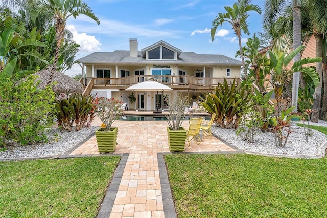 rear view of house featuring a patio, a yard, an outdoor pool, and a chimney