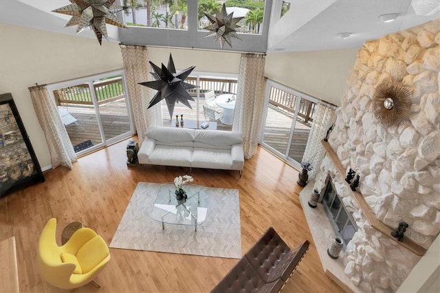 living room with high vaulted ceiling, a fireplace, and wood finished floors