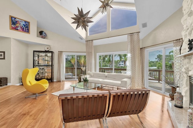 living room featuring high vaulted ceiling, wood finished floors, ceiling fan, and a fireplace