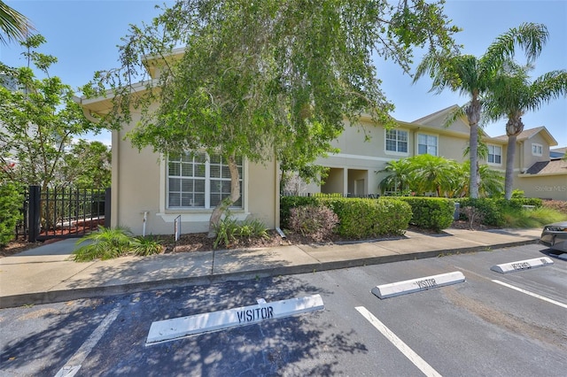 view of front of property with stucco siding, uncovered parking, and fence