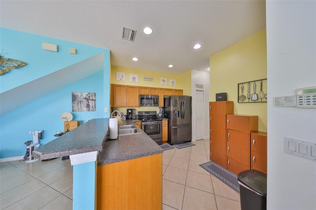 kitchen featuring visible vents, a sink, light tile patterned flooring, a peninsula, and appliances with stainless steel finishes