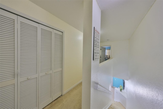 corridor featuring light carpet and baseboards