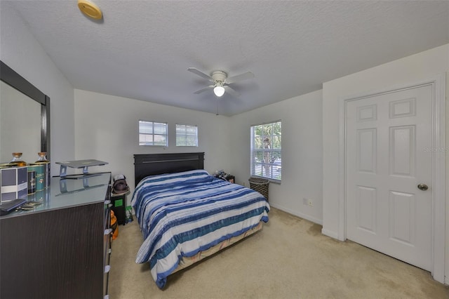 bedroom with baseboards, a textured ceiling, light colored carpet, and ceiling fan
