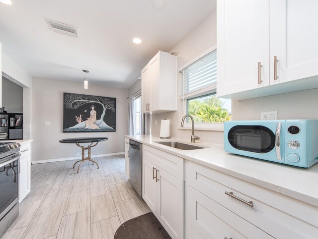 11397 122nd Ave, Largo, FL 33778 - kitchen with stainless steel appliances, a sink, light countertops, white cabinets, and baseboards