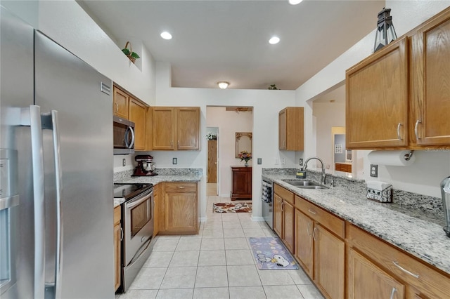 kitchen featuring light stone countertops, brown cabinets, a sink, appliances with stainless steel finishes, and light tile patterned floors
