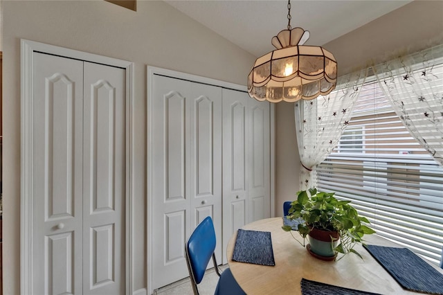 tiled dining area featuring a chandelier and vaulted ceiling