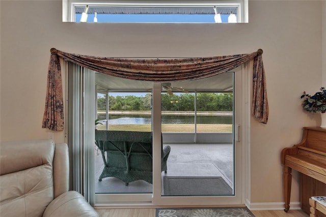 entryway with baseboards, a water view, wood finished floors, and a healthy amount of sunlight