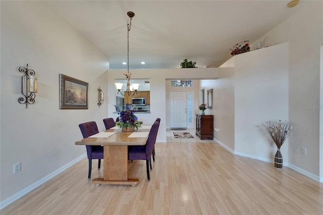 dining space featuring baseboards, light wood-type flooring, and a chandelier