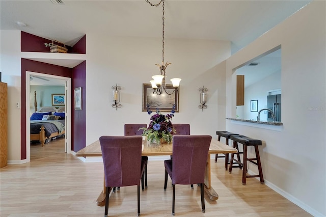 dining room featuring an inviting chandelier, visible vents, light wood finished floors, and lofted ceiling