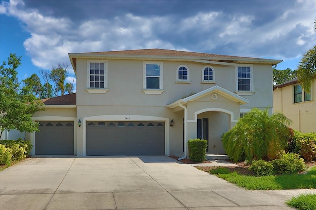 mediterranean / spanish house with stucco siding, an attached garage, and driveway