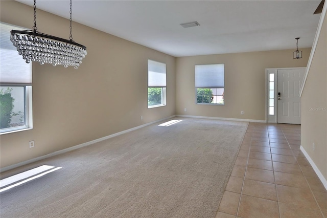 entryway with visible vents, baseboards, a notable chandelier, light colored carpet, and light tile patterned floors