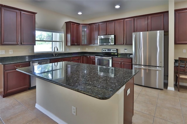 kitchen with appliances with stainless steel finishes, a sink, light tile patterned flooring, and a kitchen island
