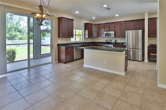 kitchen with a sink, dark countertops, a chandelier, appliances with stainless steel finishes, and light tile patterned floors